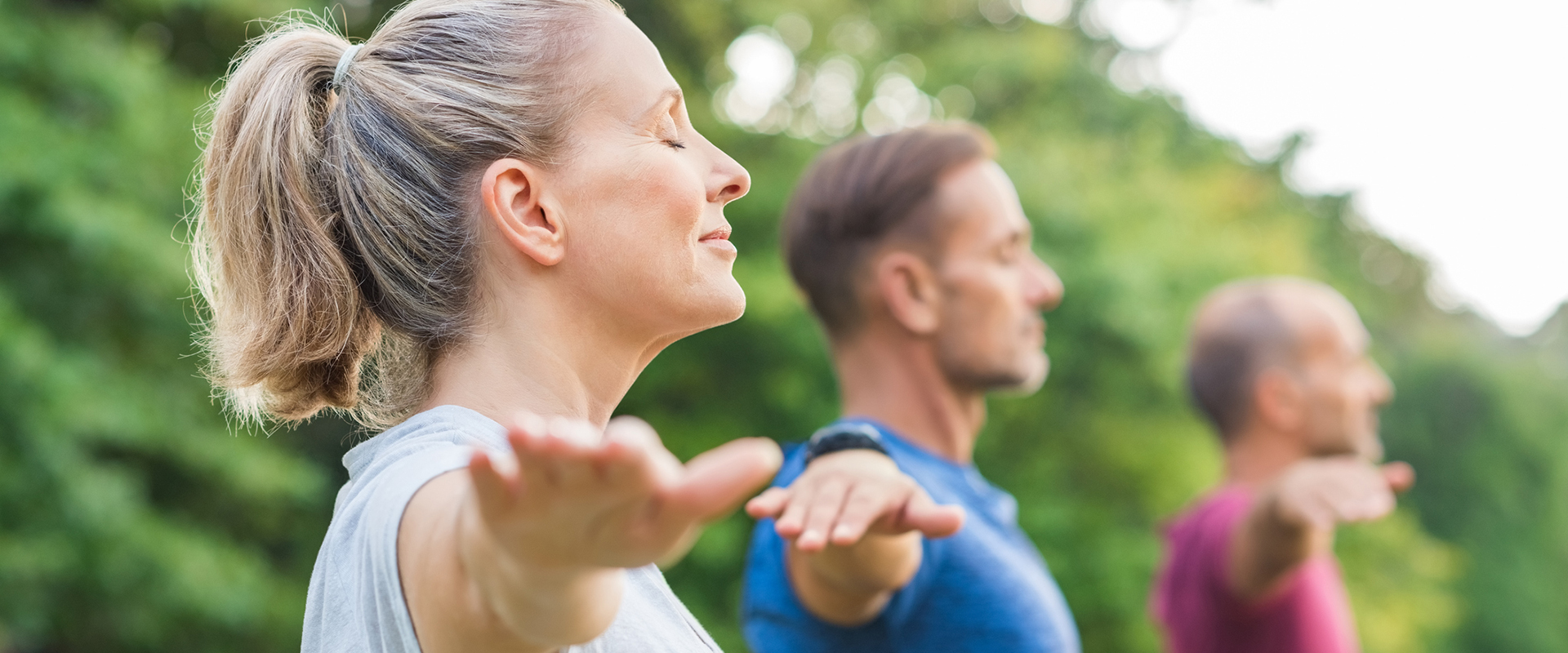 Group of three people practicing yoga outdoors