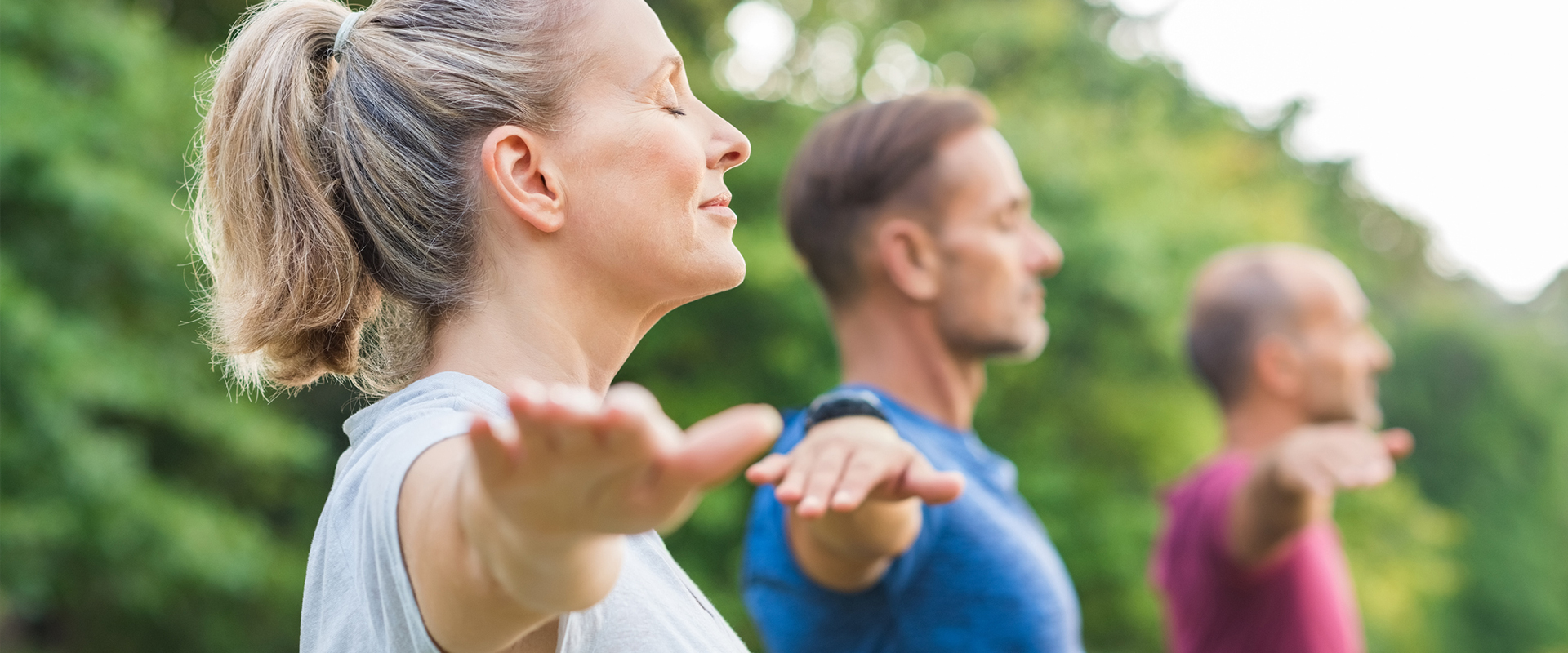 Group of three people practicing yoga outdoors